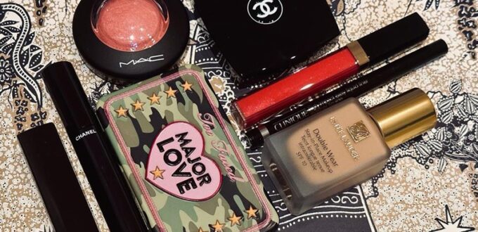 6 produse de make-up fotografiate pe un fundal cu desen grafic, care conține blush, farduri de pleoape, ruj, gloss, eyeliner lichid și fond de ten
